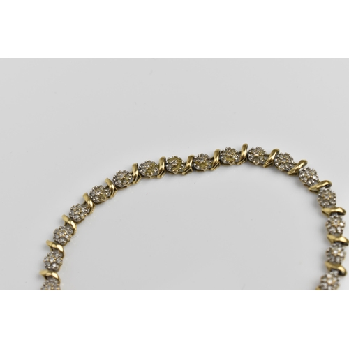 167 - A 9ct yellow gold and diamond bracelet, designed with twenty-seven floral diamond clusters, with cat... 