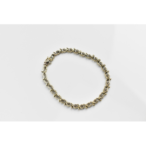 167 - A 9ct yellow gold and diamond bracelet, designed with twenty-seven floral diamond clusters, with cat... 