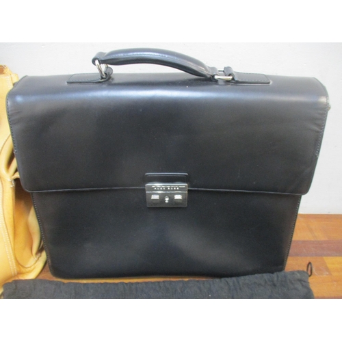 166 - Hugo Boss-A black leather briefcase in branded dustbag with key together with a light brown leather ... 