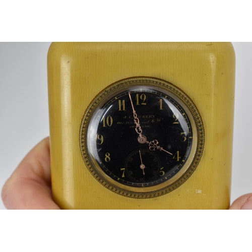 54 - An early 20th century travel/bedside clock having a black dial, with gilt hands, Arabic numerals and... 