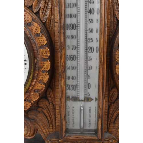 84 - An early 20th century oak combination table clock, barometer and thermometer, having a scroll carved... 