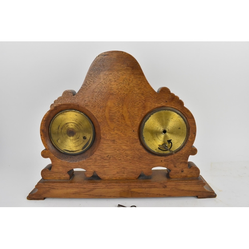 84 - An early 20th century oak combination table clock, barometer and thermometer, having a scroll carved... 