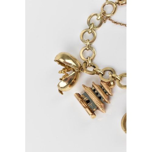 115 - A 9ct yellow gold charm bracelet, with various hanging charms, to include a carousel, bird's cage, t... 