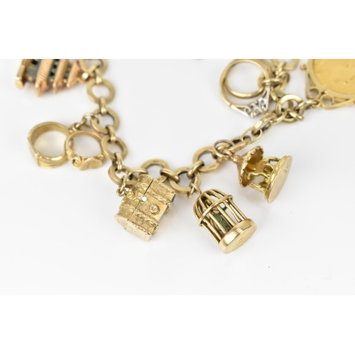 115 - A 9ct yellow gold charm bracelet, with various hanging charms, to include a carousel, bird's cage, t... 