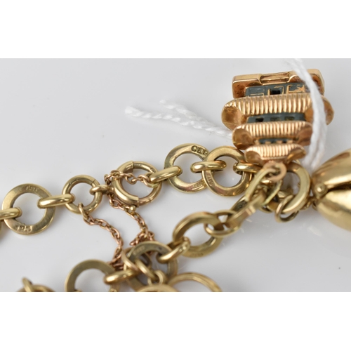 115 - A 9ct yellow gold charm bracelet, with various hanging charms, to include a carousel, bird's cage, t... 