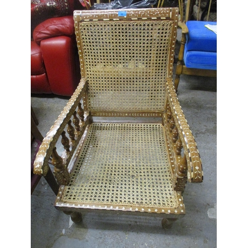 86 - A Middle Eastern inlaid teak open armchair, inlaid with ebony and bone in a floral design, cane back... 