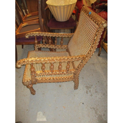 86 - A Middle Eastern inlaid teak open armchair, inlaid with ebony and bone in a floral design, cane back... 