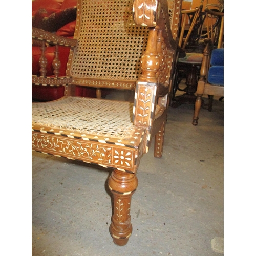 86 - A Middle Eastern inlaid teak open armchair, inlaid with ebony and bone in a floral design, cane back... 