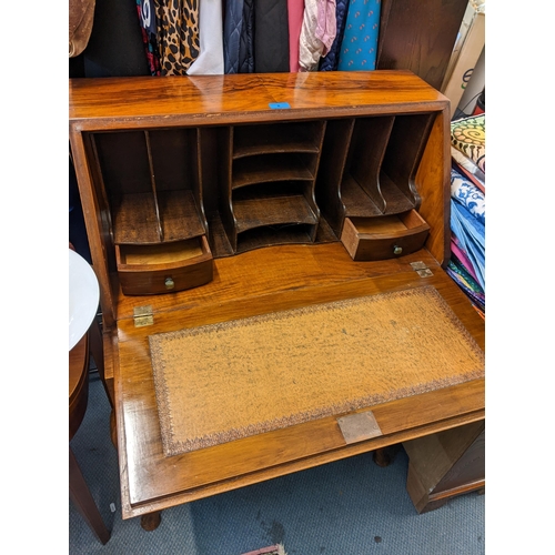 8 - An Art Deco walnut veneered desk having a fall flap with fitted interior, single drawer and on cabri... 