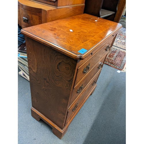 9 - A reproduction Georgian inspired elm small chest of three drawers, brush slide and on bracket shaped... 