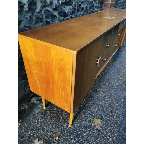 273 - A 1970s design light teak sideboard, with six drawers to the centre flanked by a cupboard door eithe... 