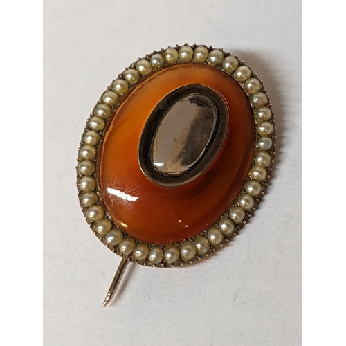 109 - A 19th century mourning brooch with an amber coloured centre and surrounded by seed pearls, 5.3g Loc... 