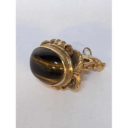 176 - A 9ct gold pendant set with a galloping horse to one side and a cabochon tigers eye to the other, 17... 