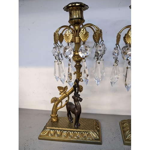 233 - A pair of mid 20th century gilt metal crystal drop candlesticks in the form of stags standing under ... 