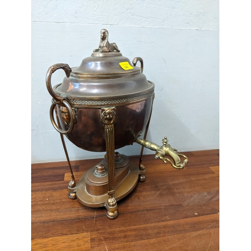 540 - A Georgian copper tea urn with a domed lid and sphinx finial, lion mask ring handles and double burn... 