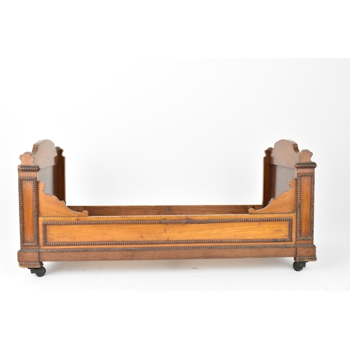 26 - A Victorian doll's mahogany sleigh bed, with beaded mouldings, on casters, 27.5 cm high x 59.5 cm wi... 