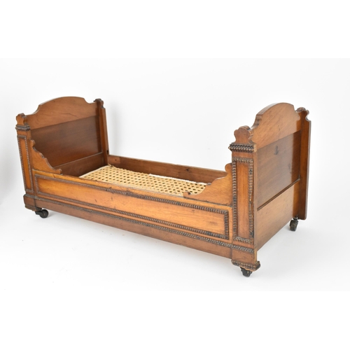 26 - A Victorian doll's mahogany sleigh bed, with beaded mouldings, on casters, 27.5 cm high x 59.5 cm wi... 