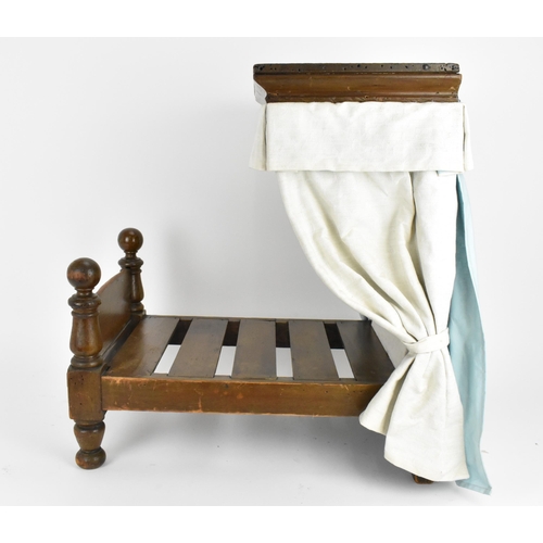 27 - A 19th century doll's half tester bed, with upholstered bed hangings and headboard, on turned feet, ... 