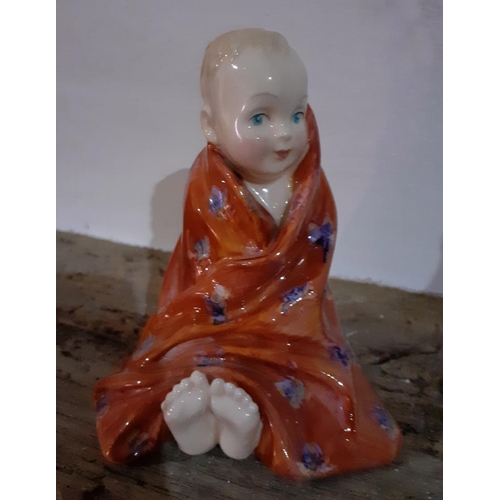 413 - A Royal Doulton 'This Little Pig' figure of a young boy wrapped up in a red blanket with his feet po... 