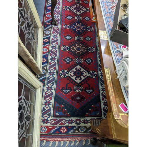 141 - A hand woven Turkish red ground runner having geometric designs and fringed ends, 317 cm x 82 cm RAM