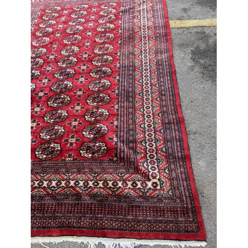 150 - A hand woven Pakistan red ground rug having elephant feet motifs with multiguard borders, 286 cm x 1... 