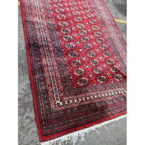 150 - A hand woven Pakistan red ground rug having elephant feet motifs with multiguard borders, 286 cm x 1... 