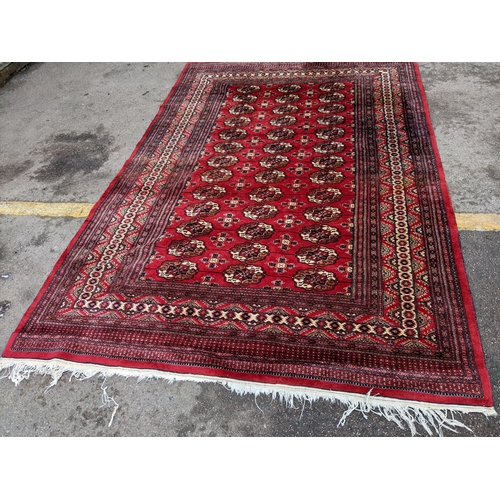 150 - A hand woven Pakistan red ground rug having elephant feet motifs with multiguard borders, 286 cm x 1... 