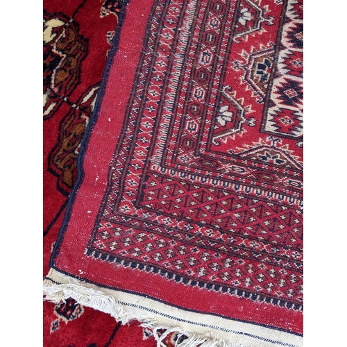 150 - A hand woven Pakistan red ground rug having elephant feet motifs with multiguard borders, 286 cm x 1... 