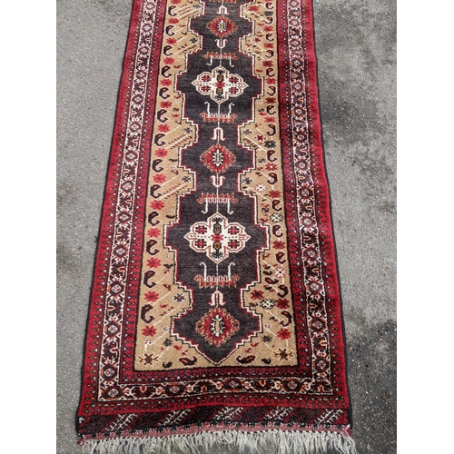 151 - A hand woven Middle Eastern red and beige ground runner having geometric designs and fringed ends, 2... 