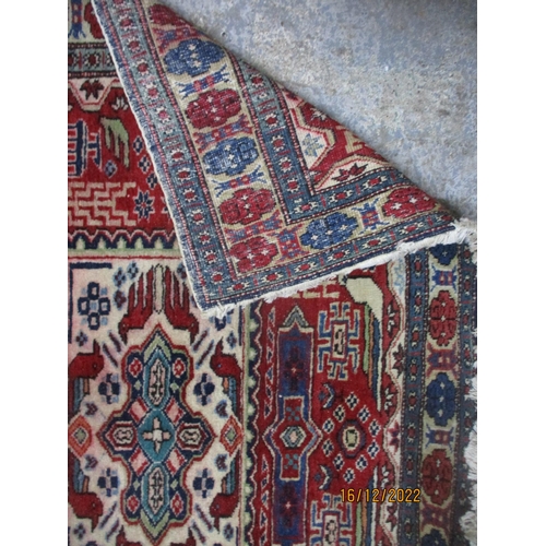 209 - Iranian hand woven red ground rug, three rectangular central panels with stylized birds and geometri... 