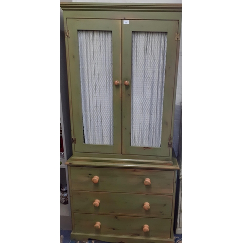 229 - A green painted cabinet in the French style with curtained and metal mesh doors above three long dra... 