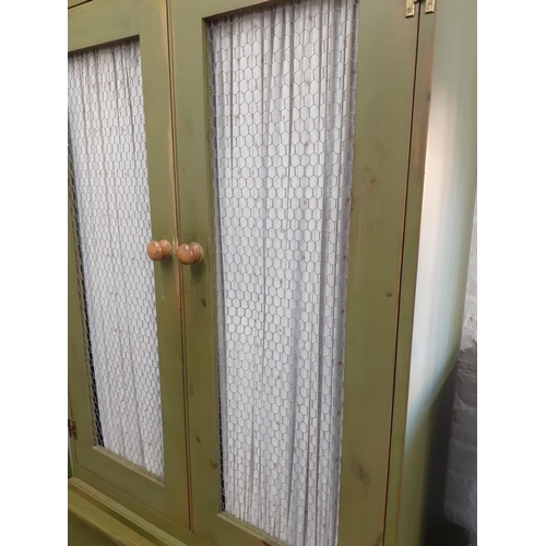 229 - A green painted cabinet in the French style with curtained and metal mesh doors above three long dra... 