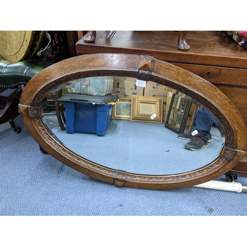 53 - An early 20th century oak oval wall hanging mirror, together with a walnut bedside cabinet Location:... 