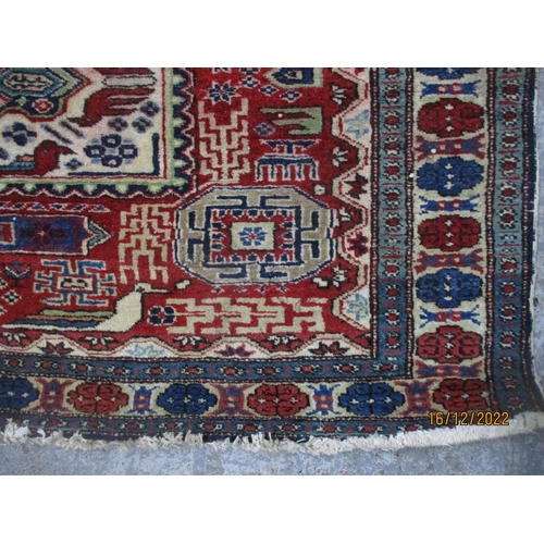 209 - Iranian hand woven red ground rug, three rectangular central panels with stylized birds and geometri... 