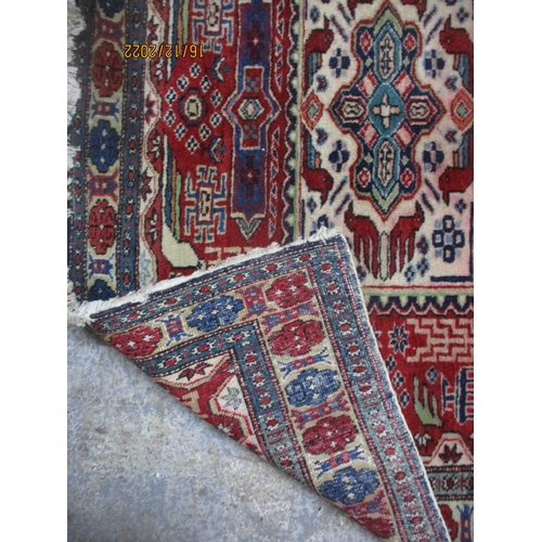 209 - Iranian hand woven red ground rug, three rectangular central panels with stylized birds and geometri... 