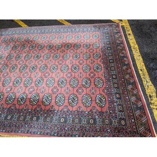 606 - A Middle Eastern machine woven red ground rug having repeating motifs and multiguard borders, 347cm ... 