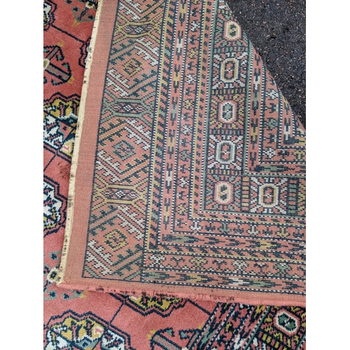 606 - A Middle Eastern machine woven red ground rug having repeating motifs and multiguard borders, 347cm ... 