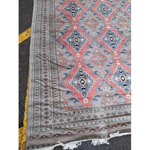 607 - A hand woven Asian red and grey ground rug having floral motifs and tasselled ends, 344cm x 261cm 
L... 