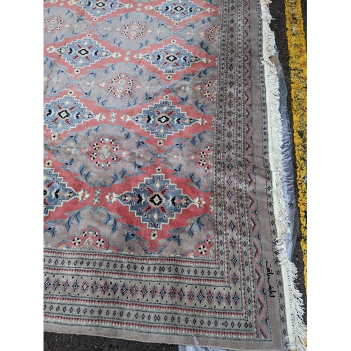 607 - A hand woven Asian red and grey ground rug having floral motifs and tasselled ends, 344cm x 261cm 
L... 