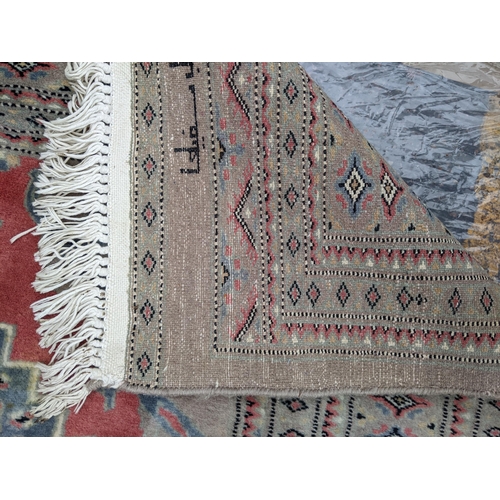 607 - A hand woven Asian red and grey ground rug having floral motifs and tasselled ends, 344cm x 261cm 
L... 