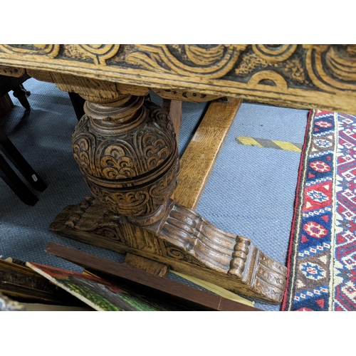 609 - An early 20th century oak draw leaf refectory table having a carved border and large bulbous support... 