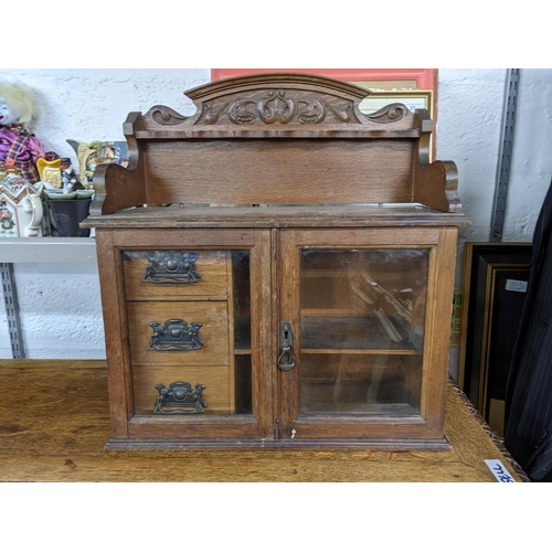 634 - An early 20th century oak smoker's cabinet with three drawers and twin glazed doors Location: BWR