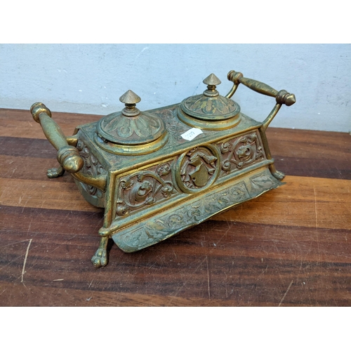 138 - A 19th century brass inkwell with two ink pots, twin handles and on lion paw feet, 9cm h x 24.5cm w
... 