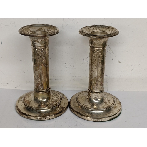 110 - A pair of Edwardian silver weighted candlesticks with Adams style decoration, Birmingham 1906, 9.5cm... 