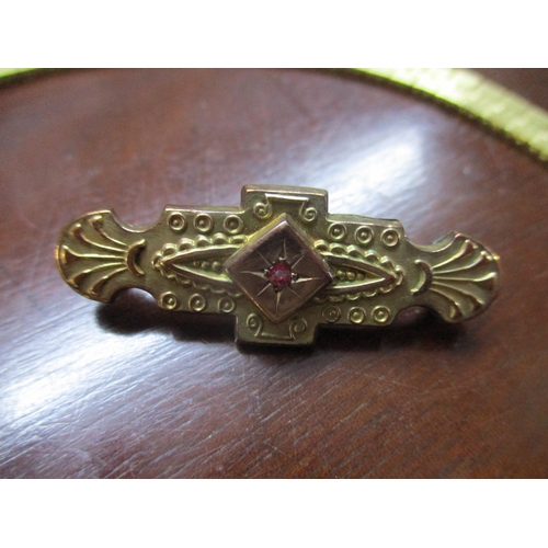 139 - A Victorian 9ct gold and gilded bar brooch set with a central red stone within an engraved star, and... 