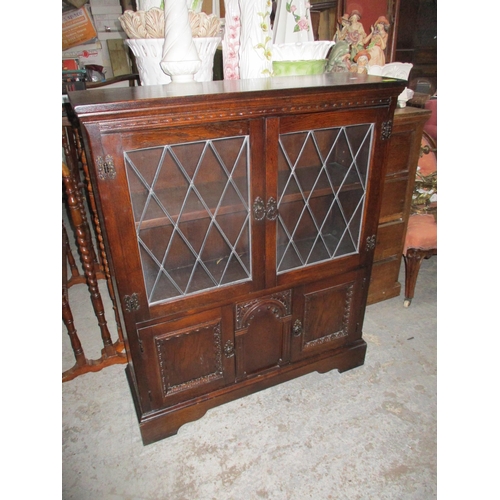 141 - An oak side cabinet, twin leaded display doors with interior adjustable shelf above twin cupboard do... 