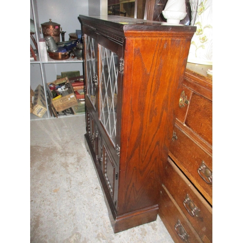 141 - An oak side cabinet, twin leaded display doors with interior adjustable shelf above twin cupboard do... 