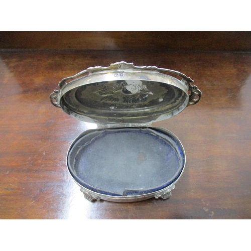 156 - An Edwardian VII silver oval dressing table box, repoussé decorated with winged heads to the lid sur... 