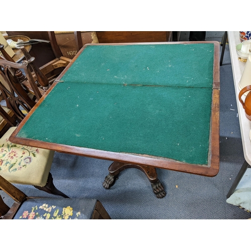 203 - An early 19th century mahogany fold over card table having a green baize, quadrafoil base and on lio... 