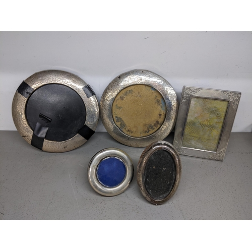 69 - Two early 20th century silver hammered circular photo frames, a silver oval frame and two white meta... 